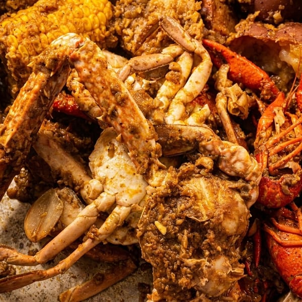 Close-up of a seafood boil with crabs, crawfish, corn, and potatoes in a metal pot.