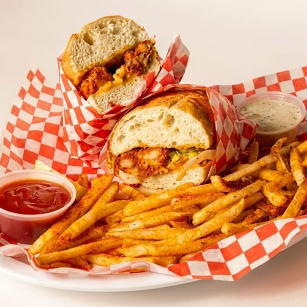 Two fried chicken sandwiches with fries, ketchup, and ranch dressing on a white plate.