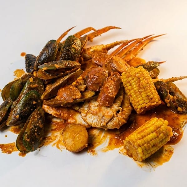 Seafood boil with mussels, crab, corn on the cob, and sausage in a rich sauce.